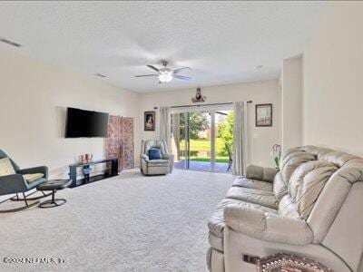 carpeted living area featuring a ceiling fan, visible vents, and a textured ceiling