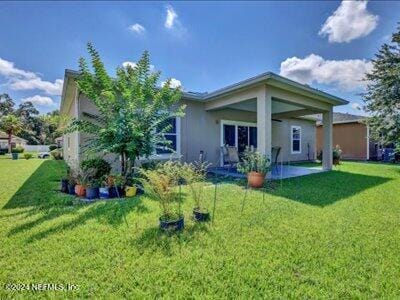 back of property with a lawn and a patio area