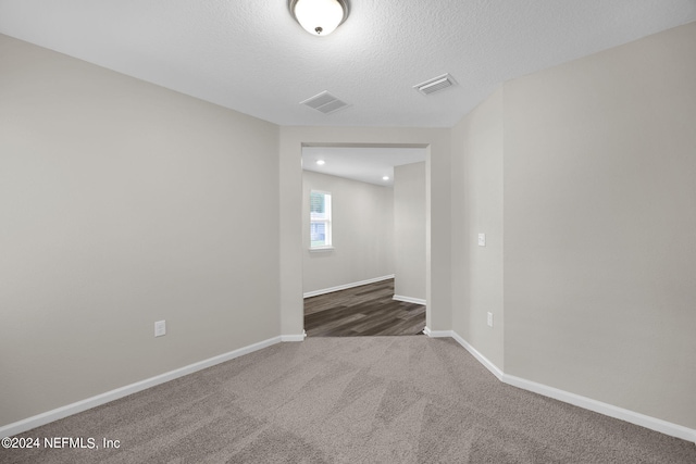 unfurnished room featuring a textured ceiling and dark colored carpet