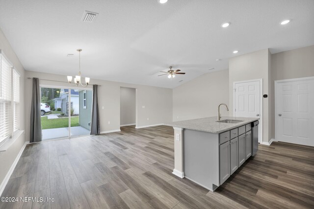 kitchen featuring ceiling fan with notable chandelier, a center island with sink, wood-type flooring, sink, and light stone counters