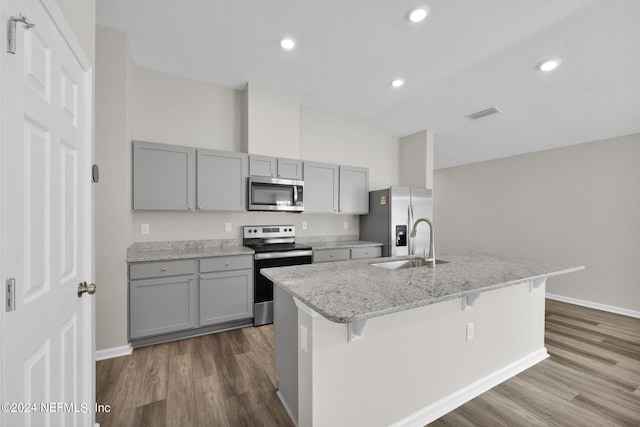 kitchen featuring a breakfast bar area, dark hardwood / wood-style flooring, a center island with sink, appliances with stainless steel finishes, and sink