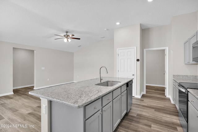 kitchen with hardwood / wood-style floors, stainless steel appliances, an island with sink, ceiling fan, and sink