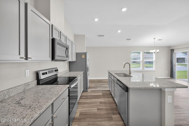 kitchen featuring a kitchen island with sink, stainless steel appliances, sink, gray cabinets, and hardwood / wood-style flooring