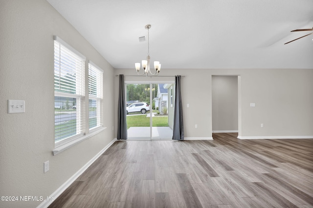 unfurnished room featuring ceiling fan with notable chandelier and light hardwood / wood-style flooring