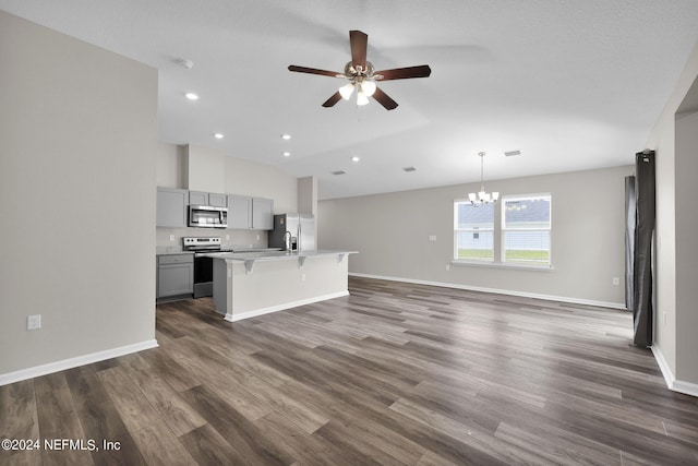 kitchen featuring gray cabinetry, ceiling fan with notable chandelier, an island with sink, dark wood-type flooring, and stainless steel appliances