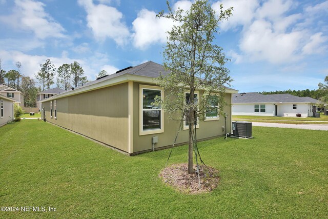 view of side of home with central AC unit and a yard