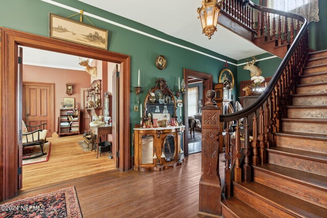 foyer entrance featuring crown molding and hardwood / wood-style flooring