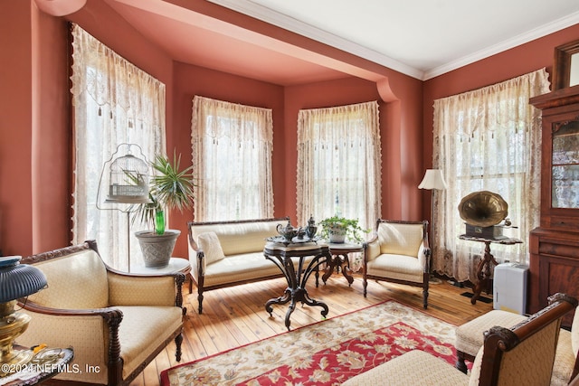 sitting room with wood-type flooring and crown molding