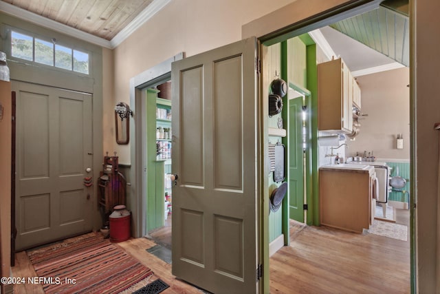 foyer entrance with light wood-type flooring, ornamental molding, and wooden ceiling