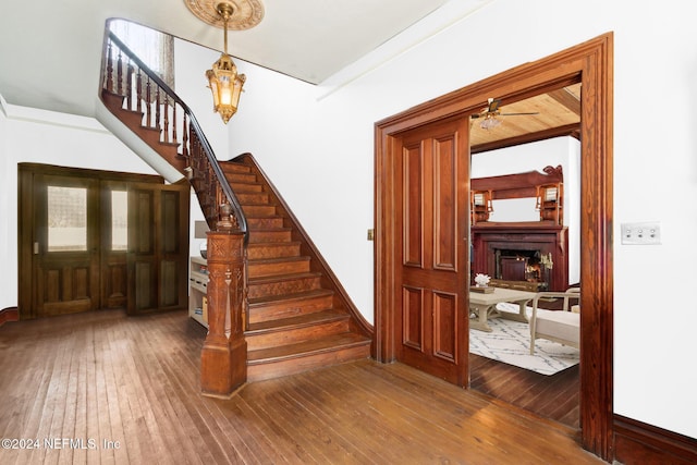 stairs with wood-type flooring and ceiling fan with notable chandelier