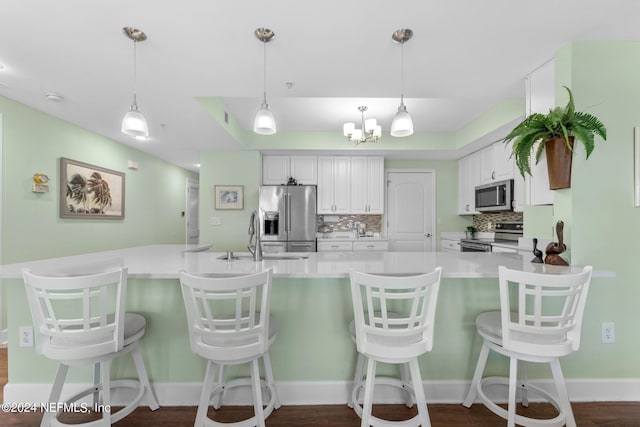 kitchen featuring white cabinetry, kitchen peninsula, stainless steel appliances, and tasteful backsplash