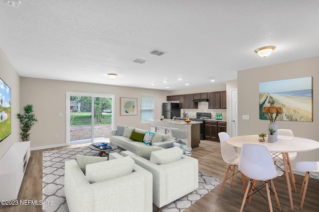 living room with a textured ceiling and light hardwood / wood-style floors