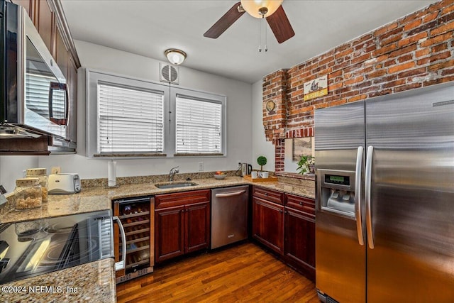 kitchen featuring appliances with stainless steel finishes, dark hardwood / wood-style floors, brick wall, wine cooler, and light stone countertops