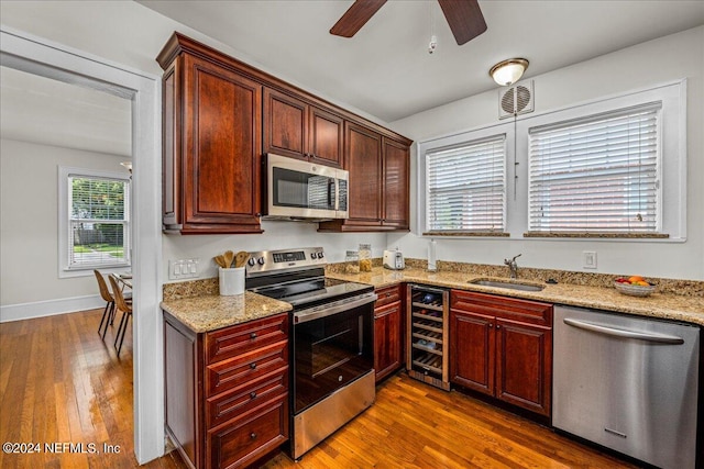 kitchen with ceiling fan, hardwood / wood-style flooring, stainless steel appliances, and beverage cooler