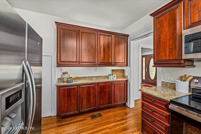 kitchen with light stone countertops, stainless steel appliances, and dark hardwood / wood-style flooring