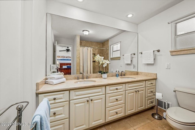 bathroom with ceiling fan, tile patterned flooring, dual bowl vanity, and toilet