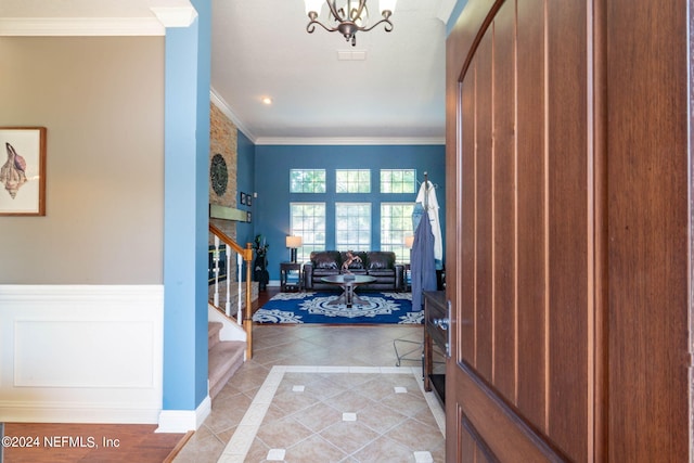 tiled entrance foyer with ornamental molding and an inviting chandelier