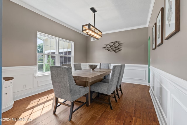 dining space with hardwood / wood-style floors, ornamental molding, and an inviting chandelier