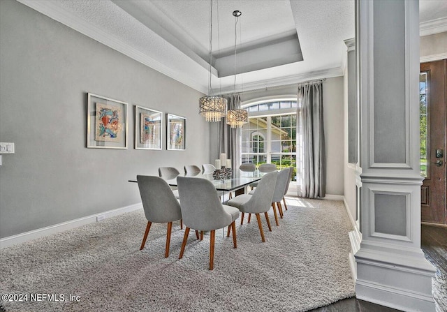 carpeted dining room featuring a textured ceiling, a tray ceiling, and crown molding