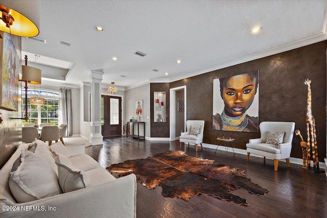 living room with a textured ceiling, crown molding, dark wood-type flooring, and ornate columns