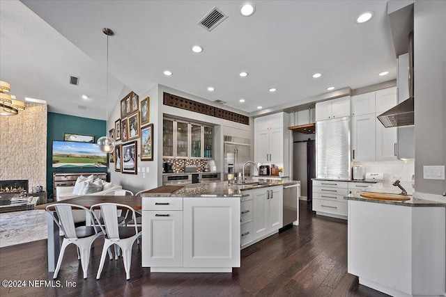 kitchen featuring pendant lighting, an island with sink, visible vents, and white cabinets