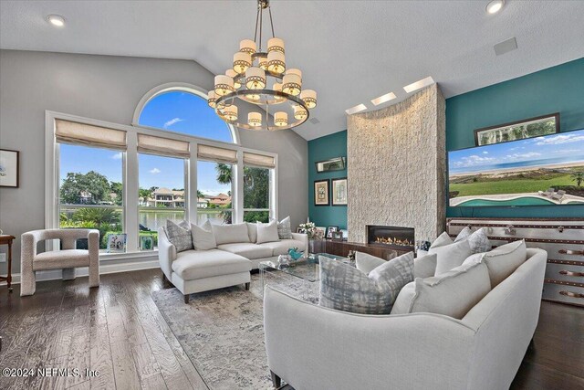 living room featuring a large fireplace, a textured ceiling, wood-type flooring, a chandelier, and lofted ceiling