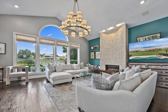 living area featuring an inviting chandelier, a large fireplace, a textured ceiling, wood finished floors, and high vaulted ceiling