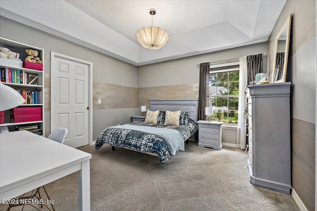 bedroom with a tray ceiling, carpet flooring, a textured ceiling, and baseboards