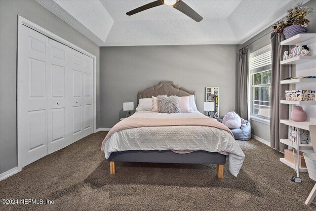 bedroom with dark colored carpet, ceiling fan, a textured ceiling, and a closet