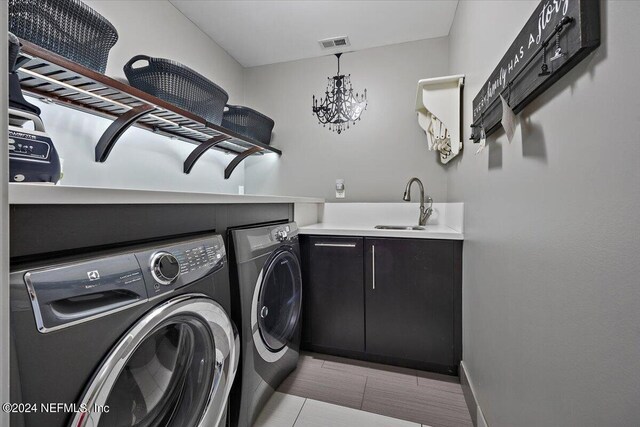 laundry room with a notable chandelier, light tile patterned flooring, washing machine and dryer, and sink