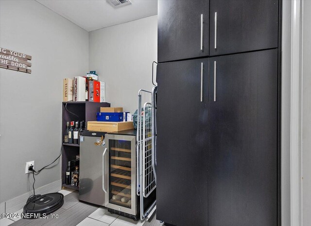 bar with wine cooler and light tile patterned floors