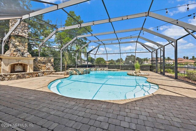 view of swimming pool with an outdoor stone fireplace, a patio, and a lanai