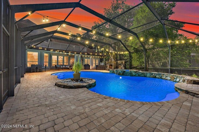 pool at dusk featuring a lanai, a patio area, pool water feature, and french doors