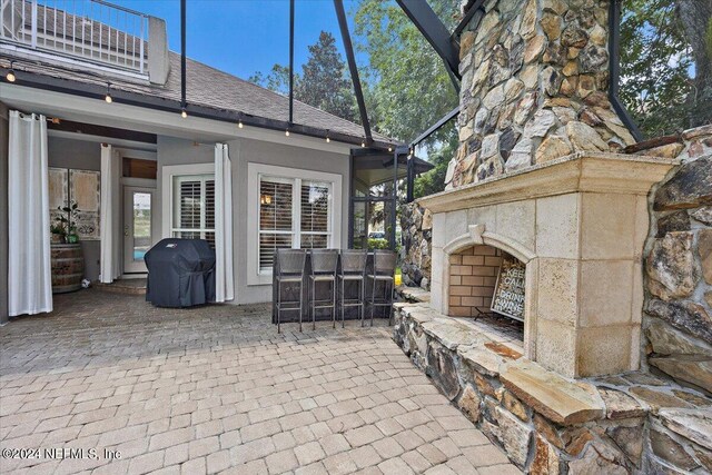 view of patio / terrace with an outdoor stone fireplace and a grill