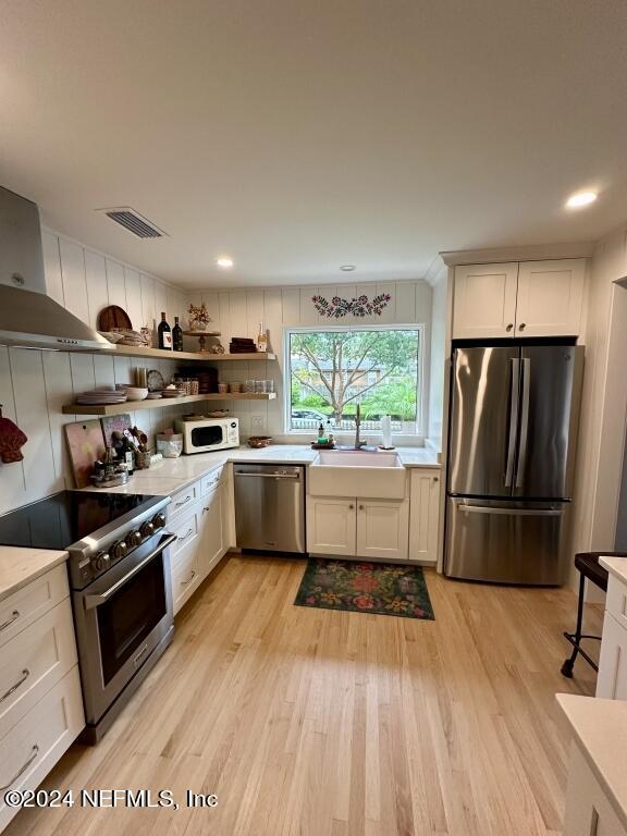 kitchen with sink, light hardwood / wood-style flooring, white cabinetry, and stainless steel appliances