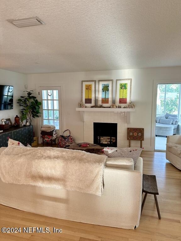 living room with light wood-type flooring, a textured ceiling, and a healthy amount of sunlight