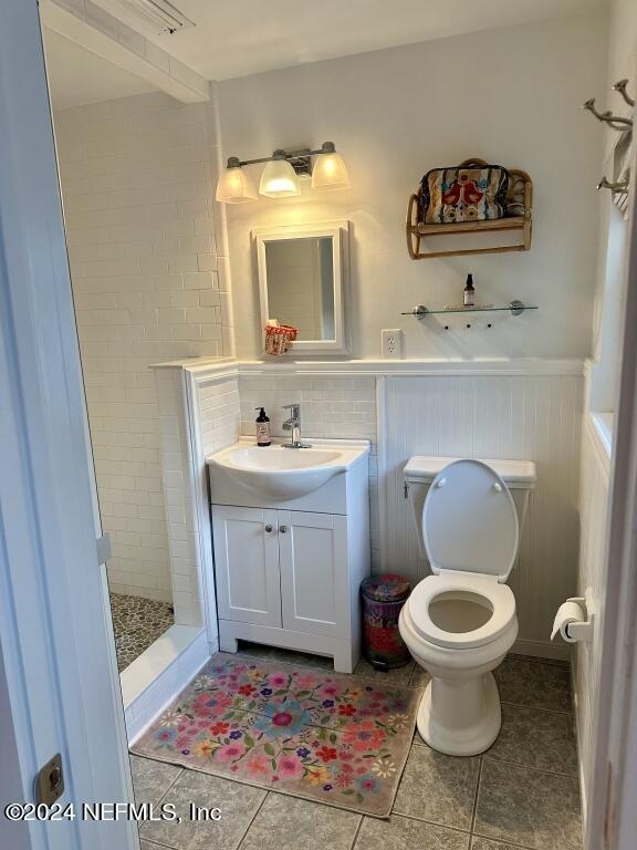 bathroom featuring backsplash, tiled shower, tile patterned flooring, vanity, and toilet