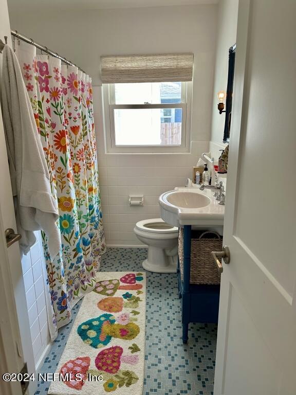 bathroom with tile walls, toilet, vanity, and tile patterned floors