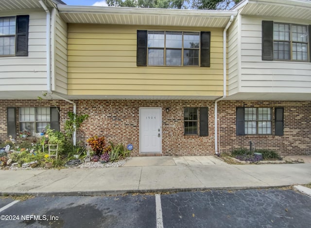 view of front of home with uncovered parking and brick siding