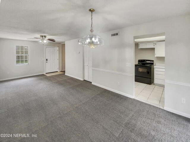 carpeted spare room featuring ceiling fan with notable chandelier