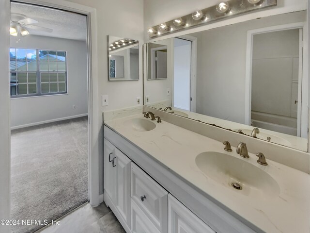 bathroom featuring ceiling fan, tile patterned flooring, a textured ceiling, and dual vanity