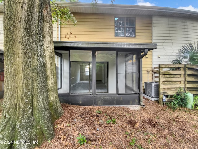 rear view of property featuring central air condition unit and a sunroom