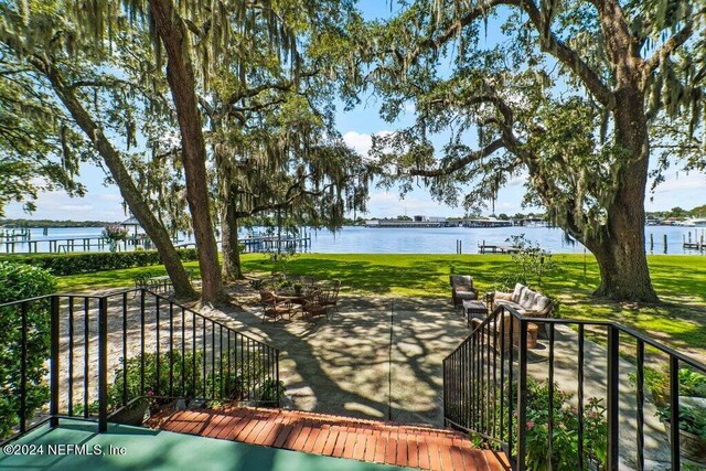 wooden deck featuring a water view, a yard, and a patio