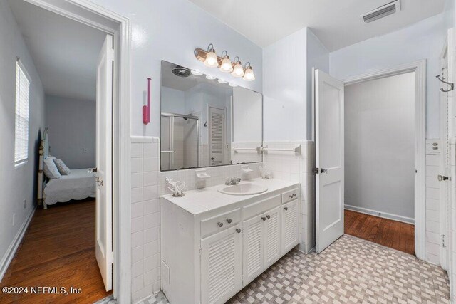 bathroom featuring a shower with door, vanity, tile walls, and hardwood / wood-style flooring