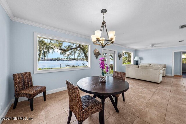 tiled dining room featuring crown molding, ceiling fan with notable chandelier, and a water view