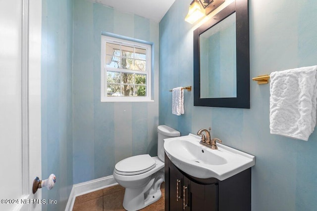 half bath featuring vanity, tile patterned floors, toilet, and baseboards