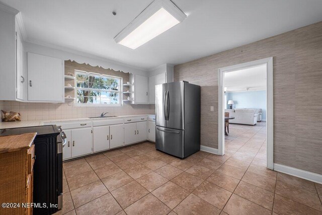 kitchen with white cabinets, light tile patterned floors, stainless steel refrigerator, sink, and ornamental molding