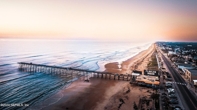 aerial view at dusk with a water view and a view of the beach