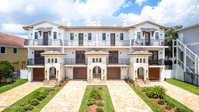 mediterranean / spanish home featuring a garage, a front lawn, and a balcony