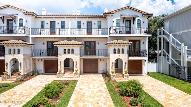 219 11th Ave S, Jacksonville Beach, FL 32250 - mediterranean / spanish-style house featuring decorative driveway, a garage, a tile roof, stucco siding, and french doors